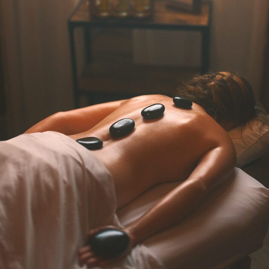 a woman laying on a bed with hot stones on her back